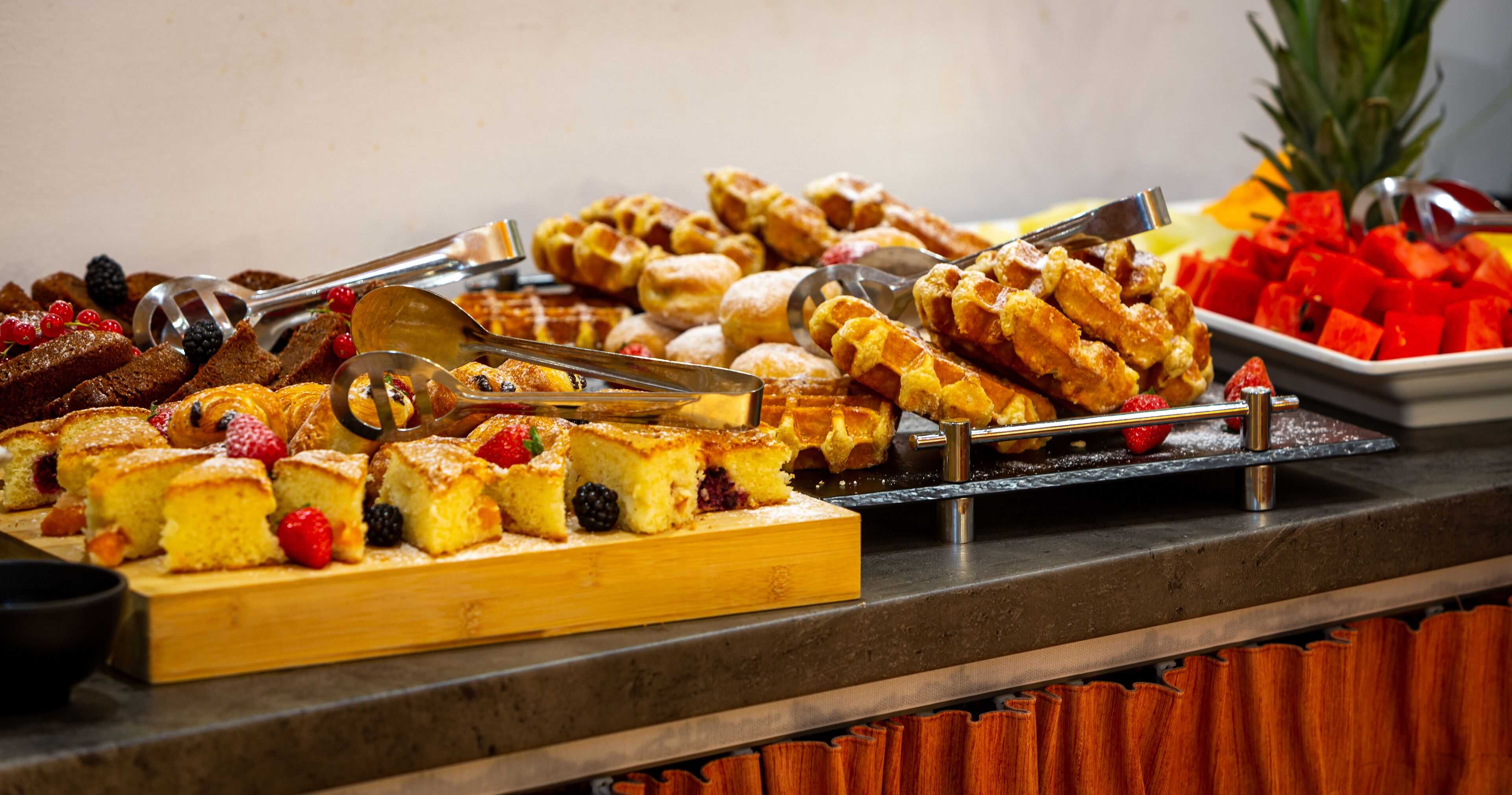 A buffet with various pastries and fruits.