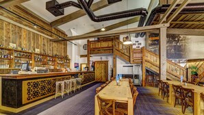 Een restaurant met houten inrichting, een bar en een trap naar een hoger gelegen verdieping.