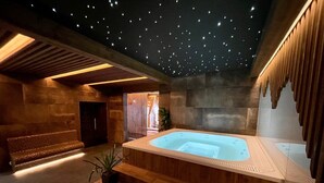 Een wellnessruimte met een jacuzzi, houten traptreden en een plafond met sterachtige verlichting.