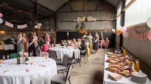 A barn-style venue with round tables, a buffet, and a festive atmosphere. - Country House, Cottage and Event Barns (Inch Cross)