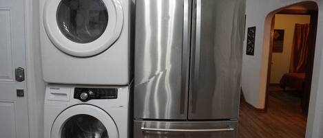 Cocina compacta con refrigerador de acero inoxidable y lavadora de carga frontal.
