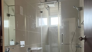 A modern bathroom with a glass-enclosed shower, a white sink, and a toilet. - Short Term Apartment in Colombo City  (Colombo)
