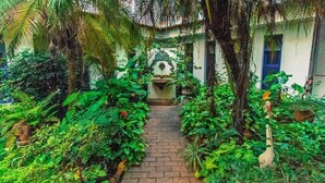 A lush garden pathway leading to a building with a blue door. - Palace Hotel de Caxambu (Caxambu)