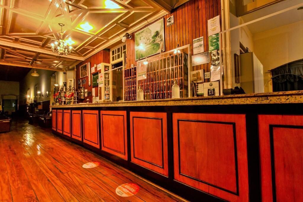Een bar met houten lambrisering, een glanzende houten vloer en een plafond met geometrische patronen.