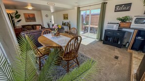 Uma sala de jantar com mesa e cadeiras, uma cozinha equipada e uma sala de estar com sofá e televisão.