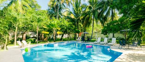 A swimming pool surrounded by palm trees and lounge chairs.