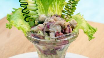 Een salade in een glazen schaal, met een limoenpartje en een decoratieve paraplu.