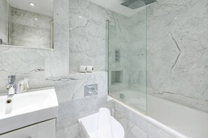 Ein modernes Badezimmer mit Marmorwaschbecken, Duschkabine aus Glas und Toilette.
