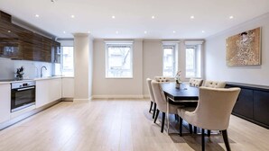 Een moderne keuken met inbouwapparatuur, een eethoek met een grote tafel en stoelen, en grote ramen die voor natuurlijk licht zorgen.