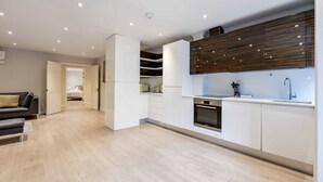 Een moderne keuken met witte kasten, een inbouwoven en een houten accentmuur.