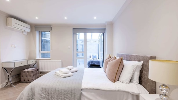 Een moderne slaapkamer met een groot bed, nachtkastje en uitzicht op de stad.
