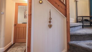 A wooden staircase with a handrail, a wall-mounted thermostat, and a shoe rack.
