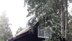 Une maison à deux étages, à l’extérieur blanc et au toit foncé, entourée d’arbres et dotée d’une allée pavée.