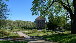 Un parco con un edificio sullo sfondo, vialetti e una panchina.