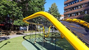 Un’area giochi con uno scivolo giallo e una rete da arrampicata.