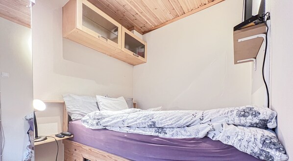 Ein Schlafzimmer mit einem Bett, einem Nachttisch, einem Spiegel und einer Holzbalkendecke.