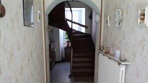 A hallway with patterned wallpaper, a tiled floor, a staircase, and a radiator. - House with fenced garden in village (Latronquière)
