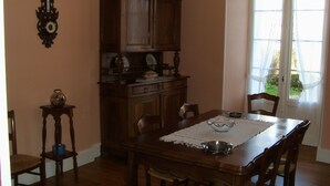 A dining room with a wooden table, chairs, a chandelier, and a cabinet. - House with fenced garden in village (Latronquière)
