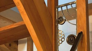 Eine Holztreppe mit Metallgeländern und einem Metallrost mit kreisförmigen Mustern.