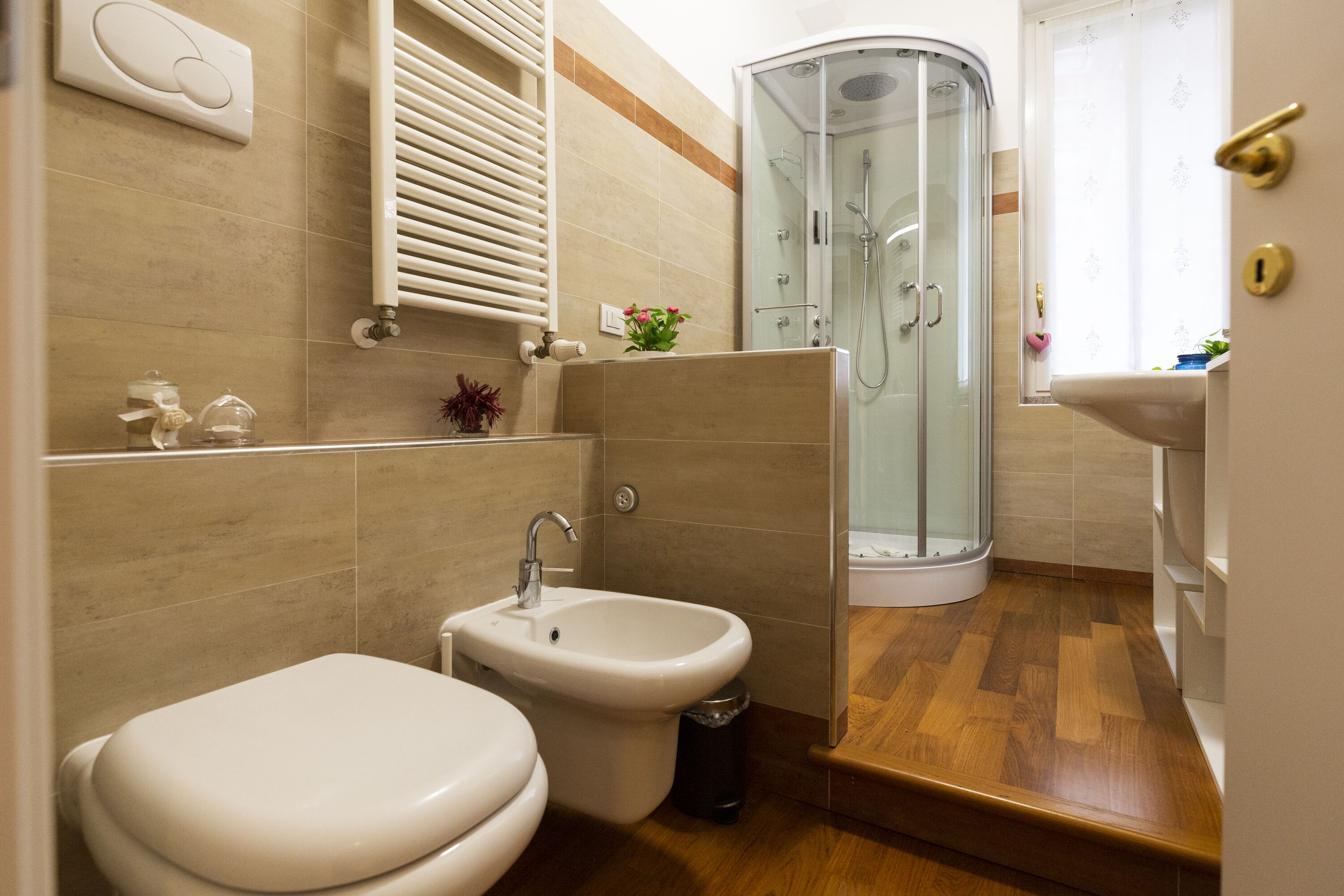 A modern bathroom with a toilet, bidet, glass shower enclosure, and a sink.