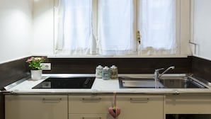 Une cuisine avec une fenêtre, un évier, une cuisinière et des placards.