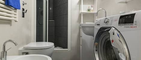 Un baño pequeño con lavamanos, inodoro y lavadora.