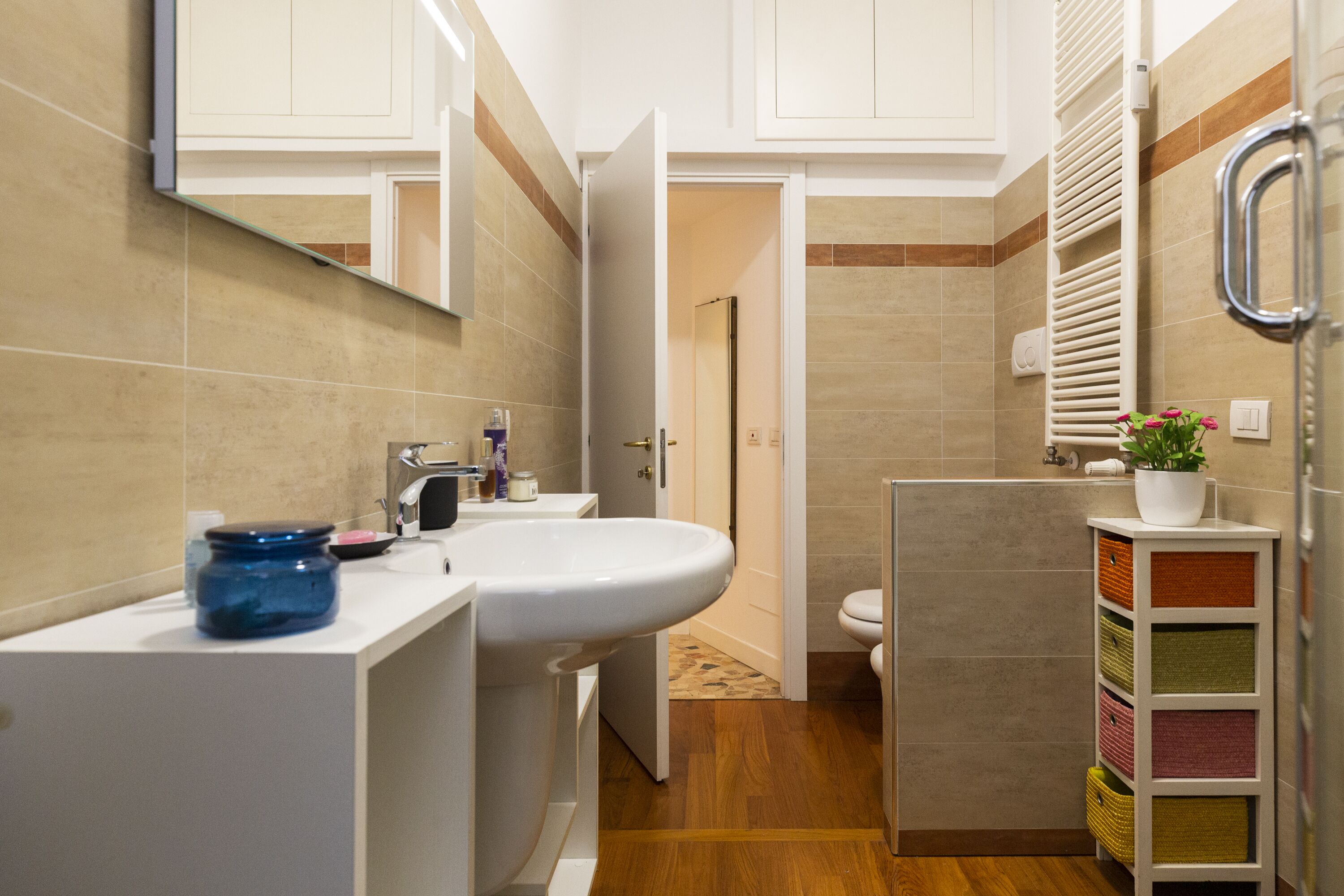 A modern bathroom with a white sink, mirror, and a shower area.