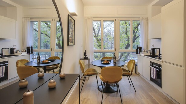 Eine moderne Küche mit Essbereich, großen Fenstern und Holzboden.