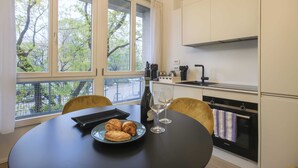 Eine moderne Küche mit Esstisch für Zwei, einer Weinflasche und Croissants.