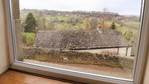 A view from a window overlooking a rural landscape with a stone wall and a traditional building with a tiled roof. - Rivendell (Holmfirth)