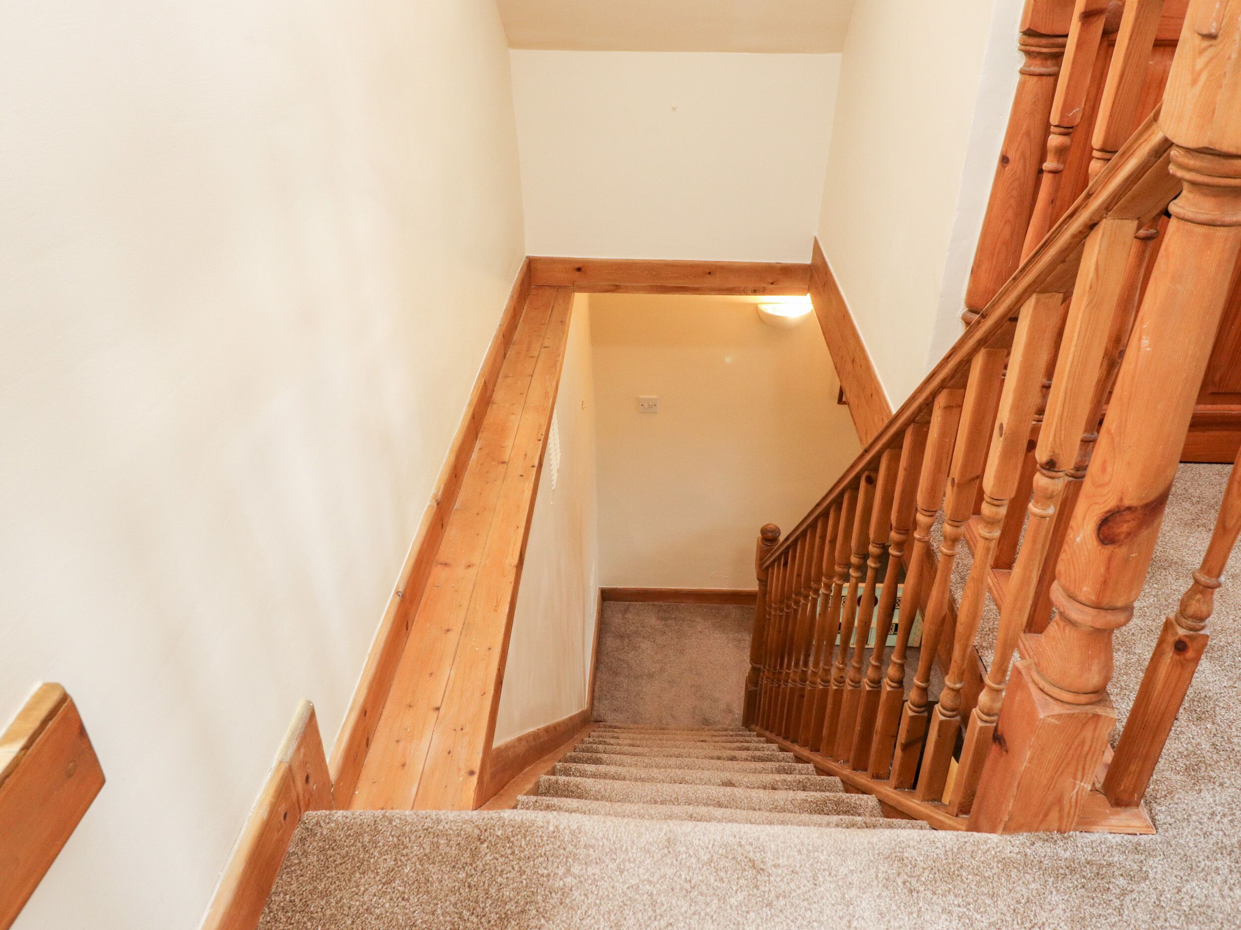 A wooden staircase with carpeted steps leading to a landing.