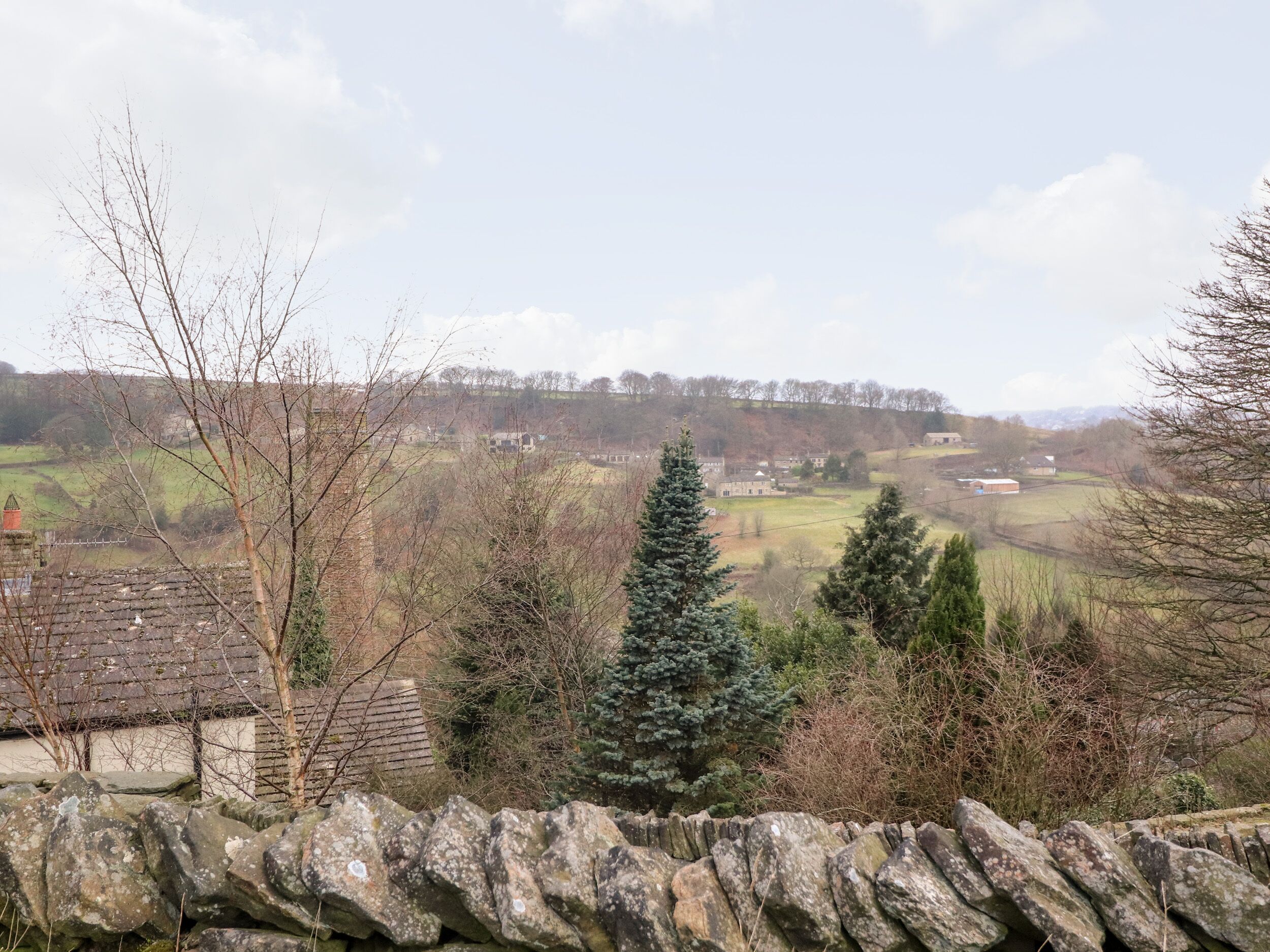 Un muro di pietra con vista su un paesaggio rurale che include case e alberi.