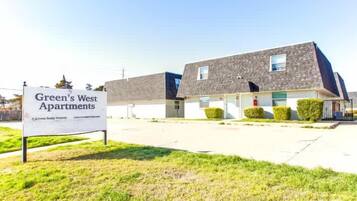Une rangée de maisons de ville à deux étages, avec une enseigne indiquant « Green's West Apartments ».