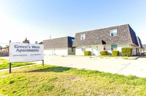 Een rij twee-onder-een-kapwoningen met een bordje voor 'Green's West Apartments'.