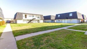 Een rij moderne twee-onder-een-doorwoningen met een grasveld en een trottoir.