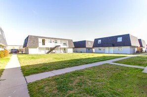 A row of modern, two-story townhouses with a central grassy area and a sidewalk.