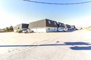 A parking lot with several cars, a building with multiple garage doors, and a clear sky.