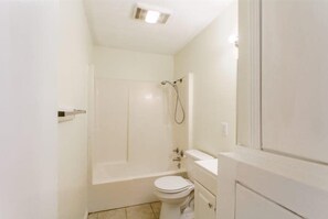 Un baño pequeño y blanco con inodoro, lavamanos y ducha.