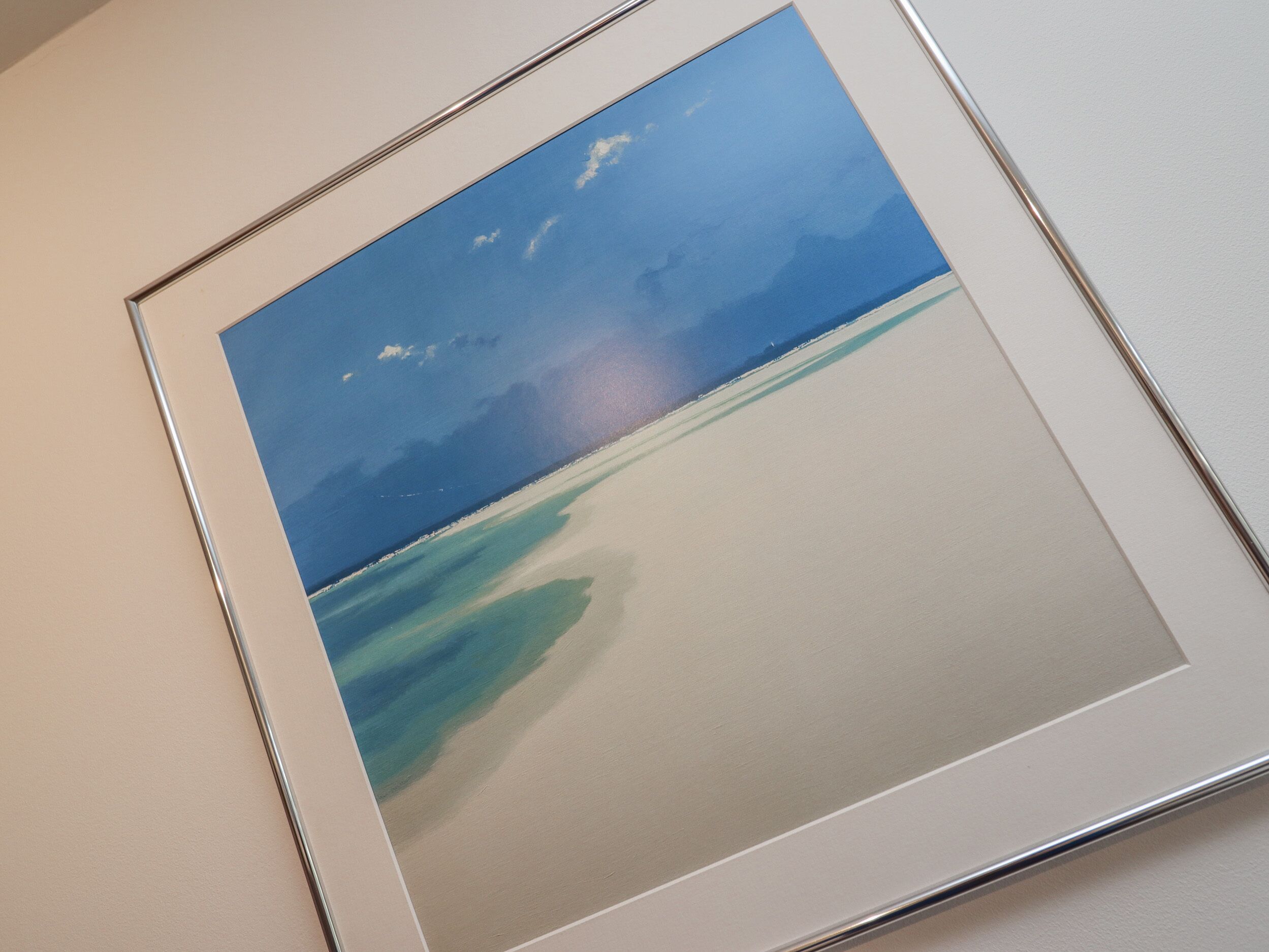 A framed photograph of a beach scene with clear skies and calm waters.