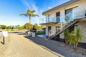 A modern building with a balcony, a staircase, and a gravel driveway. - Golden Sands (Meribula)