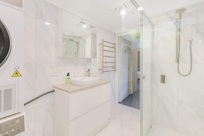 A modern bathroom with a glass-enclosed shower, a vanity with a sink, and a mirror. - Golden Sands (Meribula)