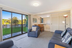 A modern living room with a sofa, armchair, and dining table.