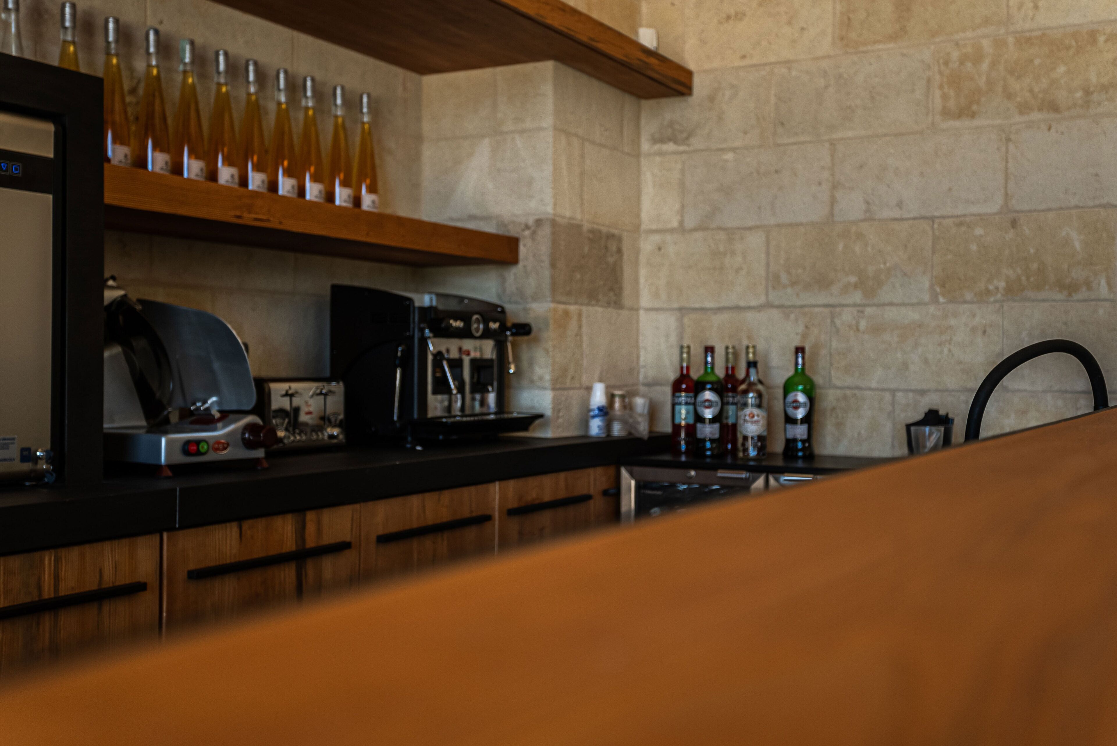 A kitchen with a coffee machine, wine bottles, and a coffee press on the counter.