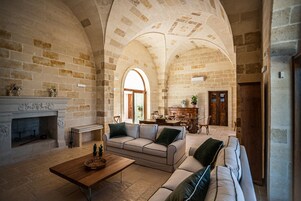 Amplia sala de estar con chimenea de piedra, un sofá, una mesa de centro y un comedor con muebles de madera.