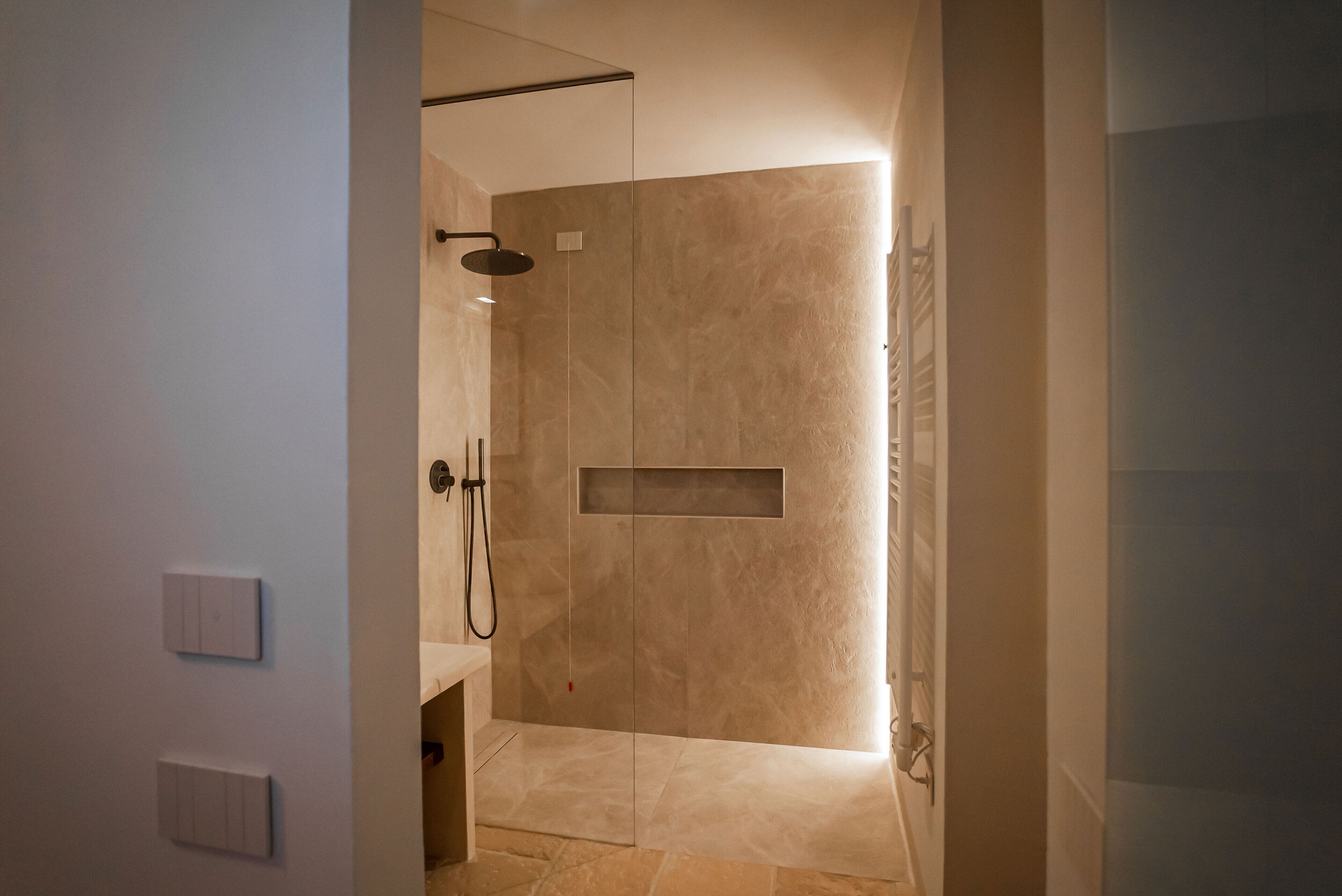 A modern bathroom with a walk-in shower, a small sink, and a toilet.