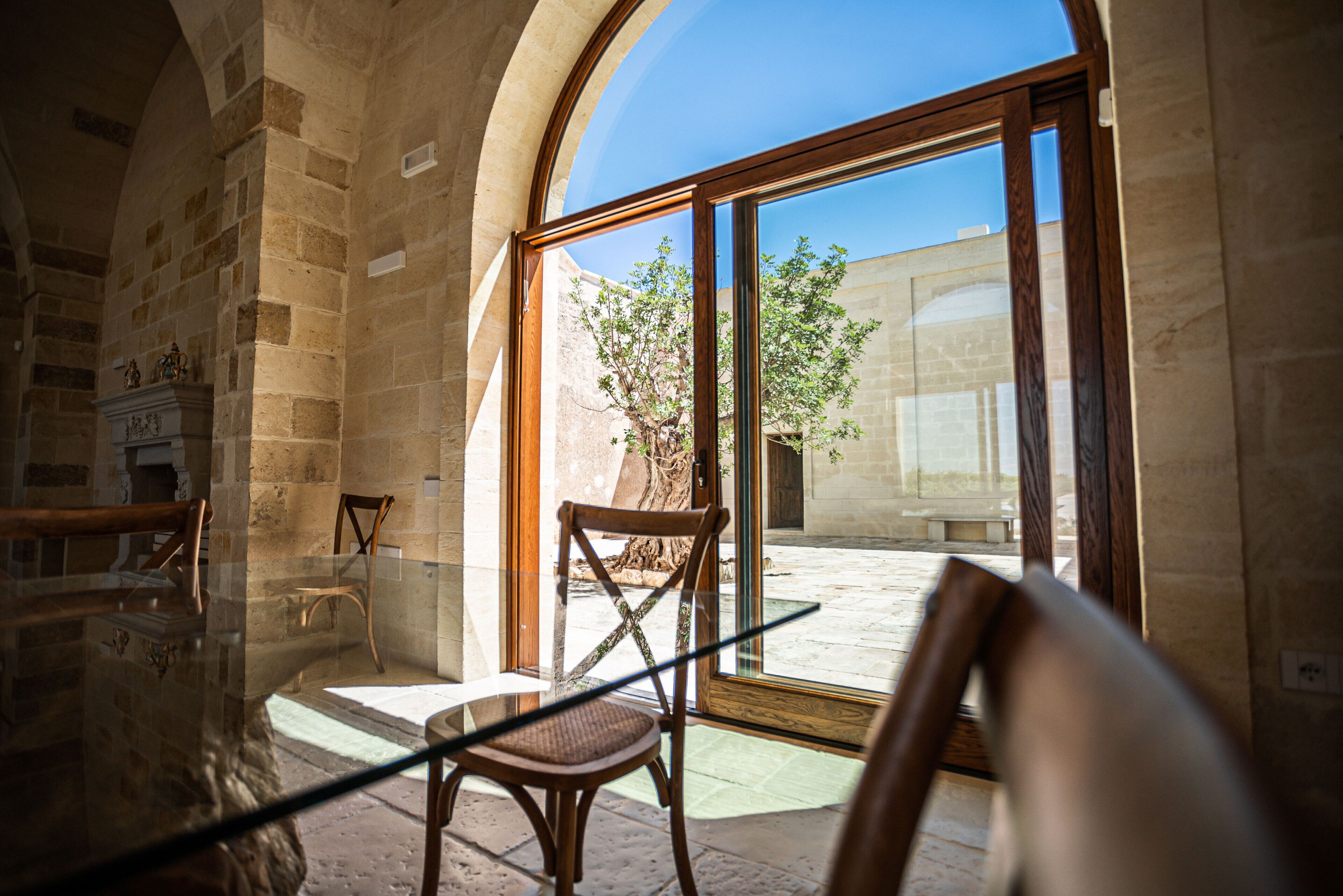 A room with stone walls, a wooden chair, and a glass door leading outside.