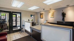 Zona de recepción con escritorio, ordenador y asientos.