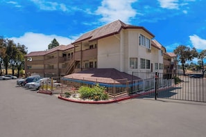 A multi-story hotel with a covered parking area and a fenced entrance.