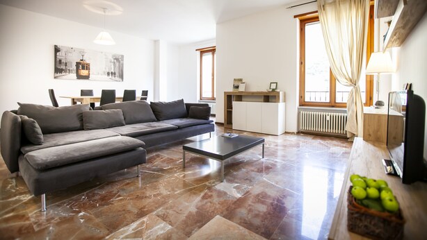 Una sala de estar moderna con un sofá gris, una mesa de centro y un comedor con mostrador de cocina.