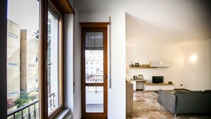 Un apartamento moderno con cocina, sala de estar y balcón con vistas a edificios.